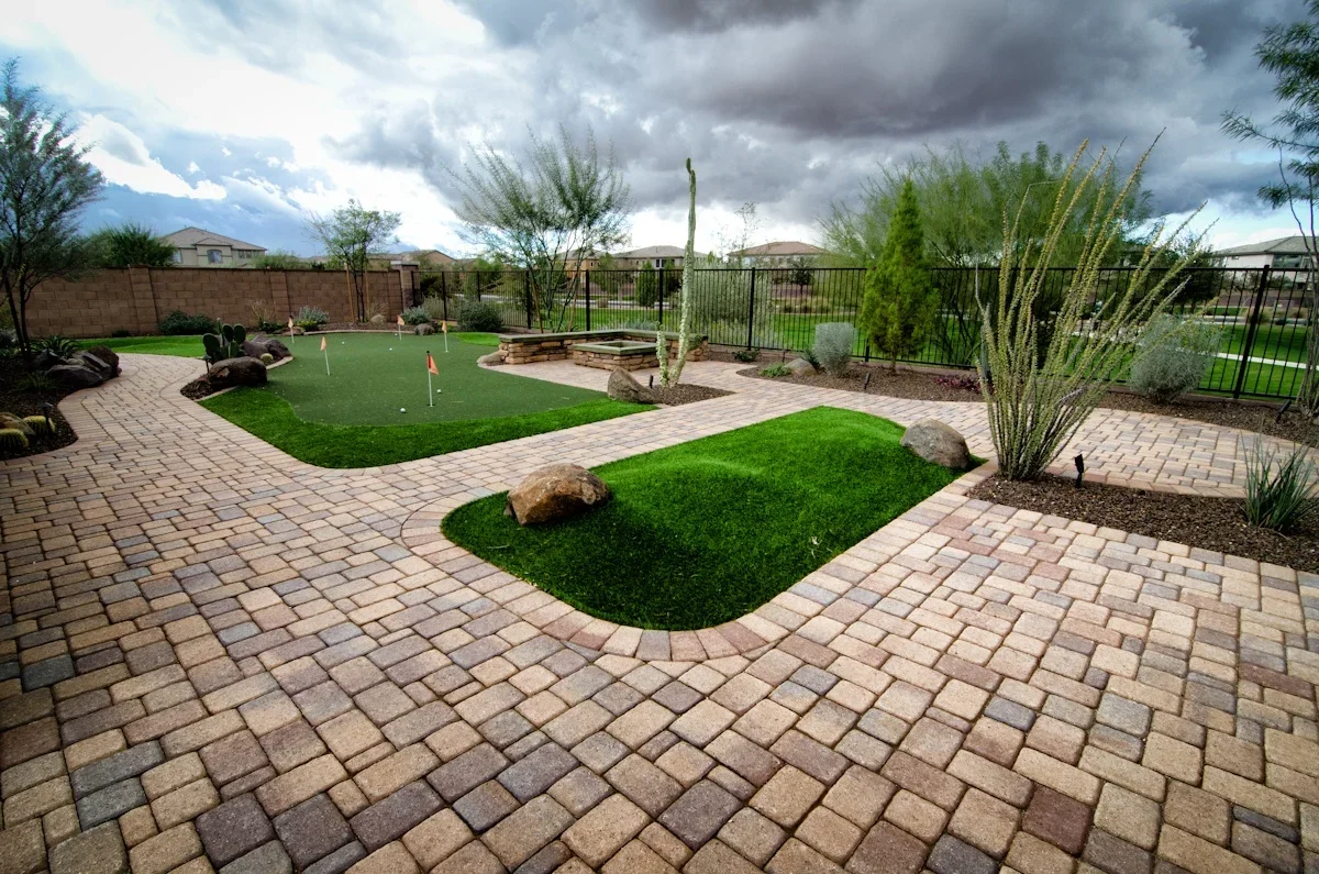 Desert backyard with artificial putting green, paver patio, and desert plants